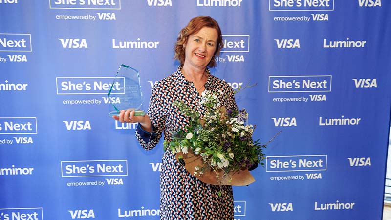 smiling woman holding flowers and shes next award